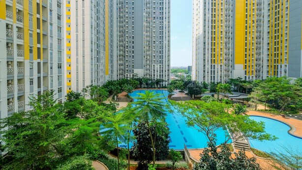 A high-rise residential building with a central swimming pool surrounded by greenery. - Strategic Studio At Springlake Summarecon Apartment Bekasi (Bekasi)