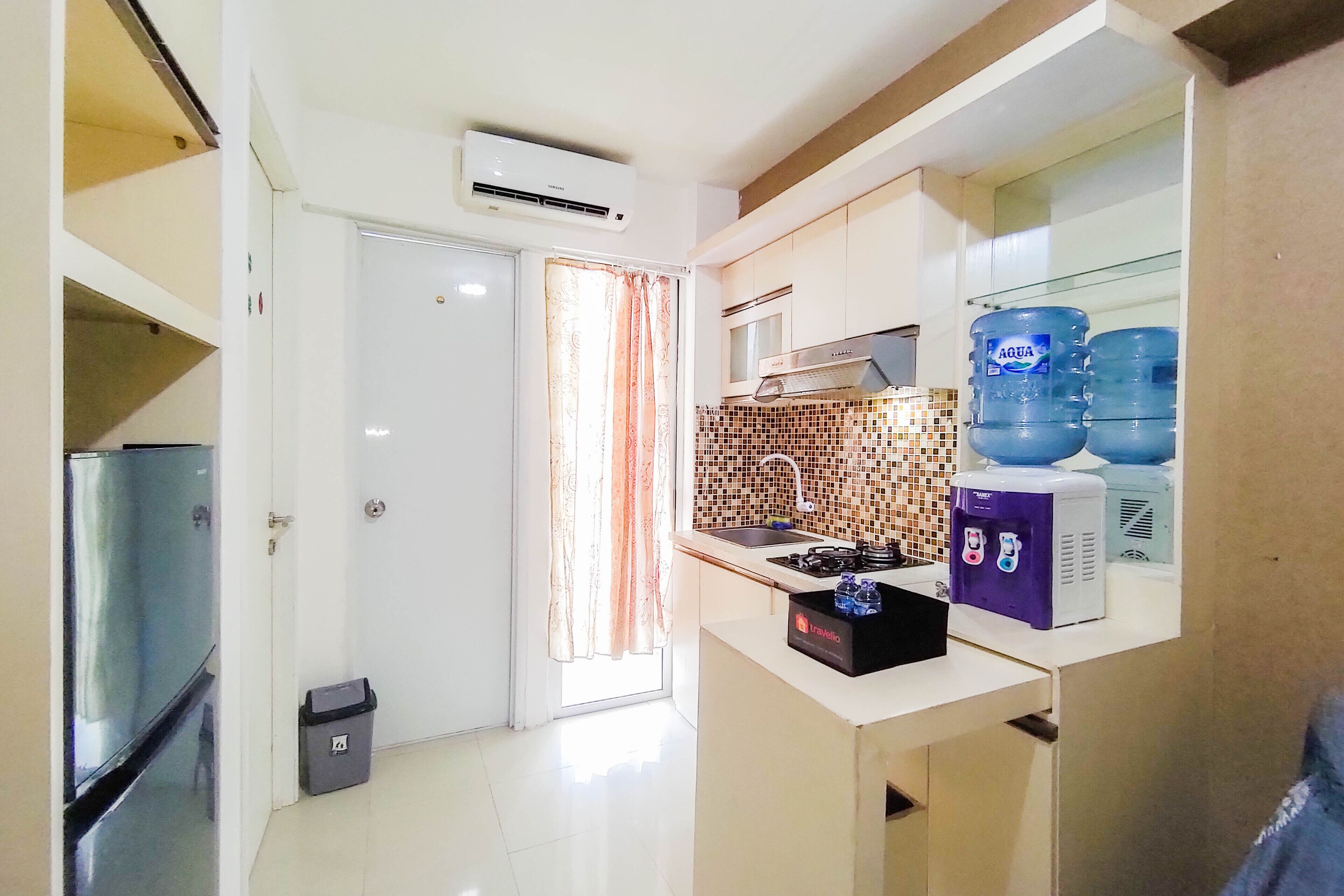 A compact kitchen with a refrigerator, microwave, and water dispensers.