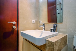 A bathroom with a white sink, a mirror, and a wooden door.