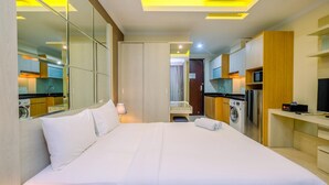 Habitació d'hotel amb un llit gran, una rentadora, una televisió i un mirall.