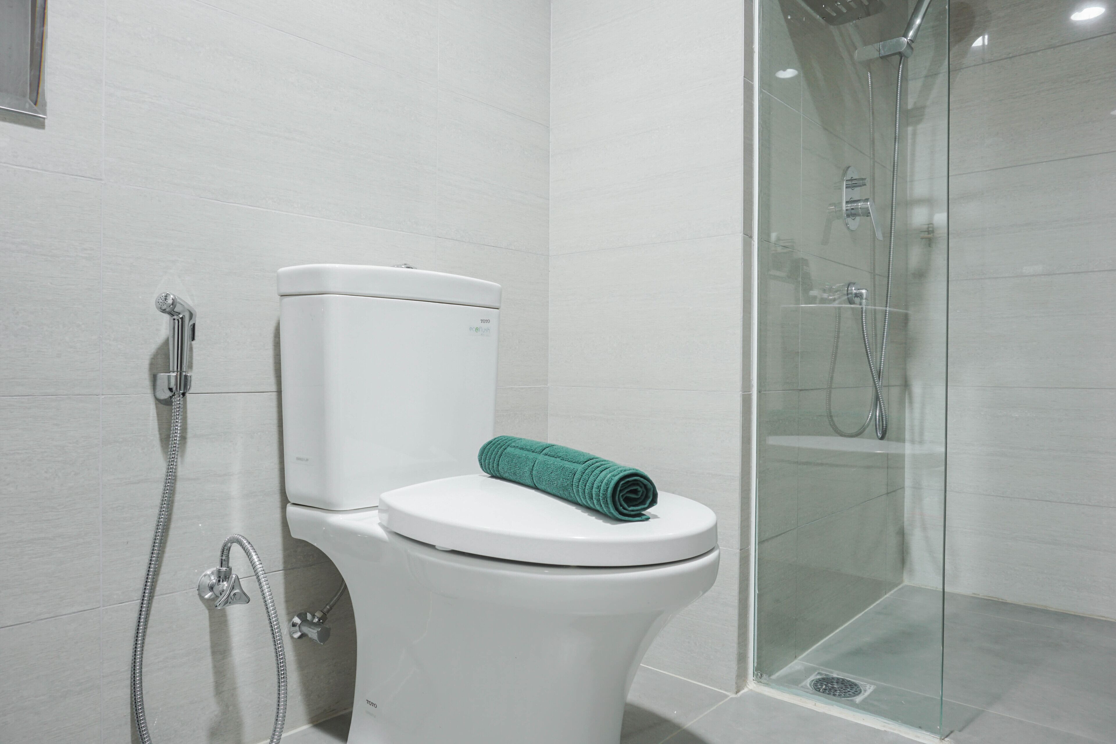 Une salle de bain moderne équipée de toilettes, d’une douche et d’un espace de douche fermé par des parois en verre.