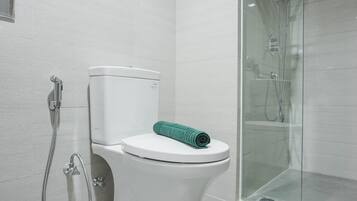 Une salle de bain moderne équipée de toilettes, d’une douche et d’un espace de douche fermé par des parois en verre.