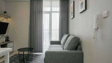 A modern living room with a grey sofa, a small round table, and a TV on a white stand.