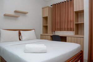 A hotel room with a bed, a desk with a chair, and built-in shelves. - Homey And Cozy Living 1Br Apartment At Atlanta Residences (Depok)