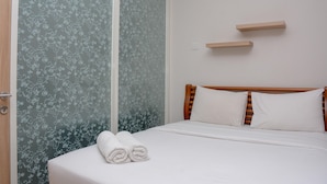 Ein ordentlich bezogenes Bett mit weißen Leinen und Kissen, ein hölzerner Kopfteil und eine Wand mit Blumenmuster-Tapete.