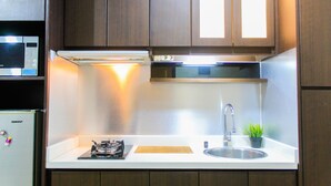 Une cuisine moderne équipée d’un four à micro-ondes encastré, d’une cuisinière à gaz, d’un évier en acier inoxydable et d’armoires en bois.