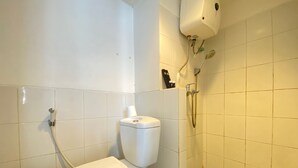 A bathroom with a toilet, a shower, and a tiled floor. - Spacious Studio Apartment At Jarrdin Cihampelas (Bandung)