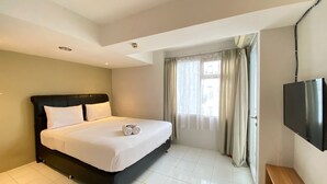 A hotel room with a bed, a TV, and a window with curtains. - Spacious Studio Apartment At Jarrdin Cihampelas (Bandung)