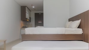A modern hotel room with a wooden headboard, a double bed, a small bedside table, and a built-in wardrobe. - Homey And Comfort Studio At The Enviro Apartment (Cikarang)