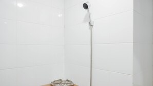A shower with a handheld showerhead and a floor-mounted control. - Comfy Studio Green Pramuka City Apartment Near Mall (Jakarta)