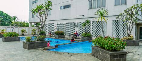 A modern building with a swimming pool surrounded by planters and outdoor seating.