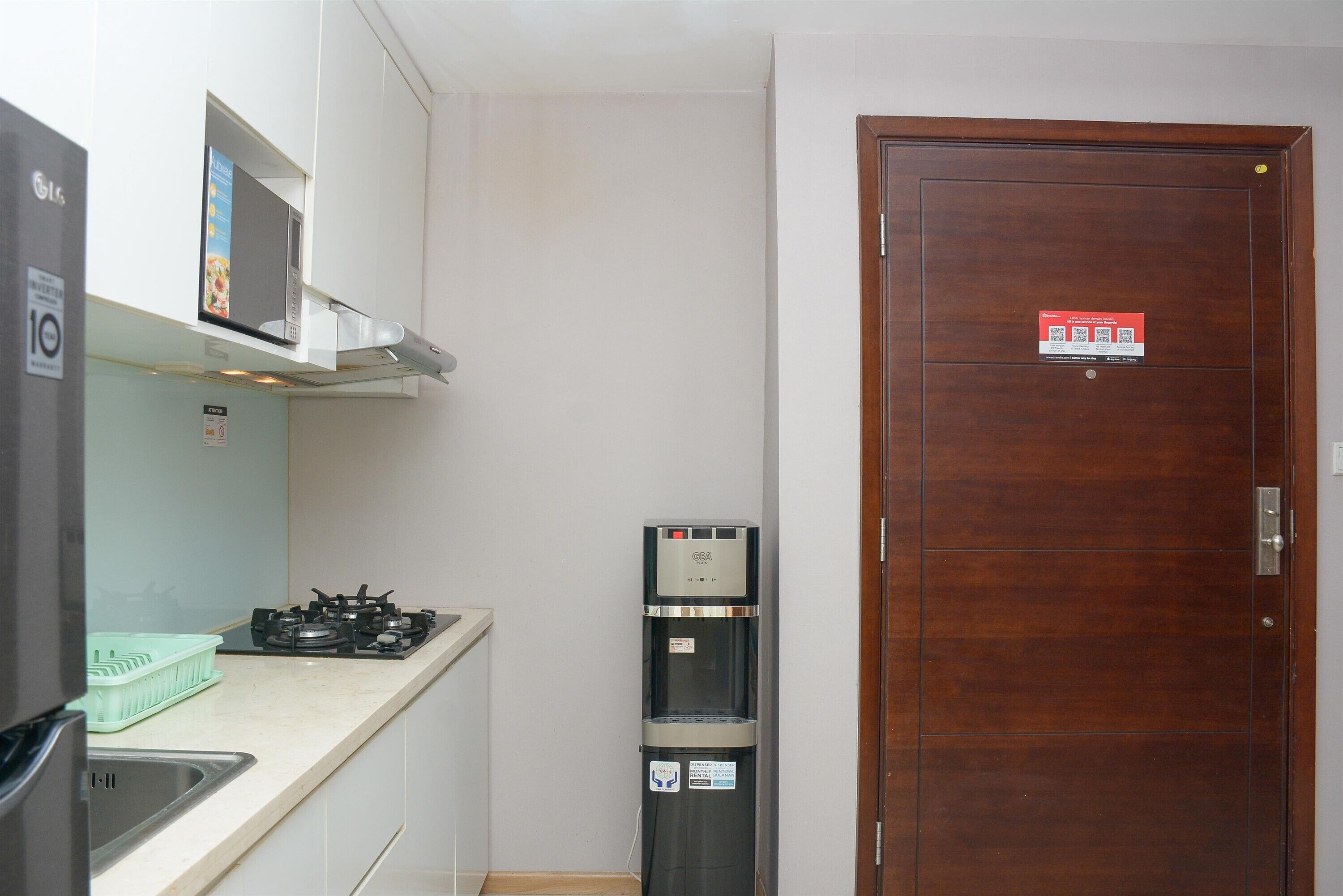 A compact kitchen with a gas stove, a microwave, and a water dispenser.