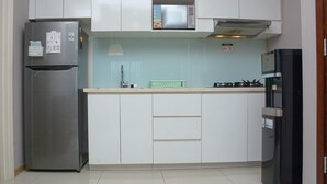 A compact kitchen with a refrigerator, microwave, stove, and sink.