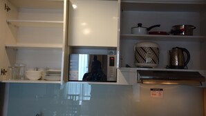 A compact kitchen with a microwave, a kettle, and a coffee maker on the countertop.
