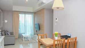 A modern living room with a sofa, TV, dining table, and chairs.