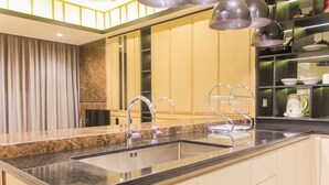 A modern kitchen with a granite countertop, stainless steel sink, and overhead lighting. - Comfort And Spacious 3Br At Branz Bsd City Apartment (Pagedangan)