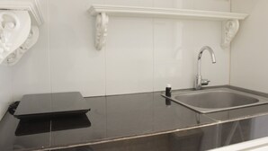 A kitchen with a black countertop, a stainless steel sink, and white decorative moldings. - Elegant & Stylish Studio At Gateway Pasteur Apartment (Cimahi)