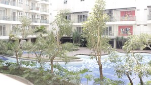A residential building with multiple balconies, a swimming pool, and surrounding greenery. - Elegant & Stylish Studio At Gateway Pasteur Apartment (Cimahi)