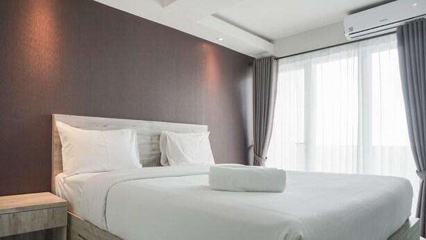 Ein modernes Hotelzimmer mit einem großen Bett, einem Nachttisch aus Holz und einem Fenster mit Vorhängen.