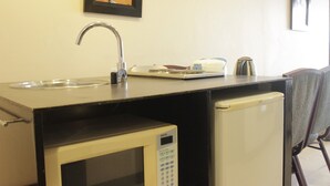 A kitchenette with a sink, microwave, and small refrigerator.
