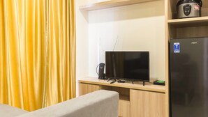 A hotel room with a TV, a coffee maker, and a refrigerator. - Luxurious 2Br At Meikarta Apartment (Cikarang)