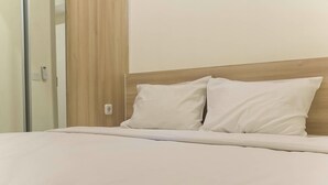 A neatly made bed with white bedding and pillows, a wooden headboard, and a light switch on the wall. - Luxurious 2Br At Meikarta Apartment (Cikarang)