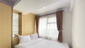 A hotel room with a bed, a mirror, and a window with curtains. - Relaxing 2Br Apartment At The Jarrdin Cihampelas (Bandung)