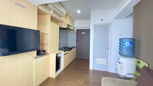 A modern kitchen with wooden cabinets, a black countertop, and a built-in oven. There is a water dispenser on the right side. - Relaxing 2Br Apartment At The Jarrdin Cihampelas (Bandung)