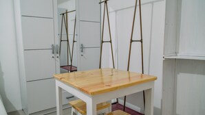 A room with a wooden table and chairs, white walls, and a door with a metal handle.