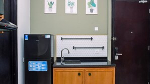 A kitchen with a black refrigerator, wooden cabinets, a sink, and three potted plants on the wall.
