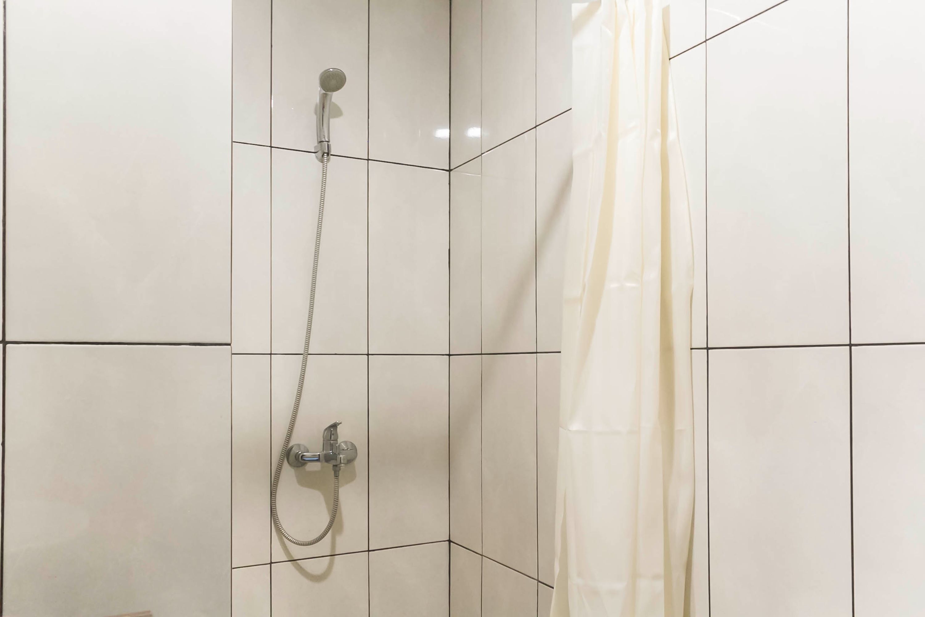 A shower area with a handheld showerhead and a wall-mounted faucet.