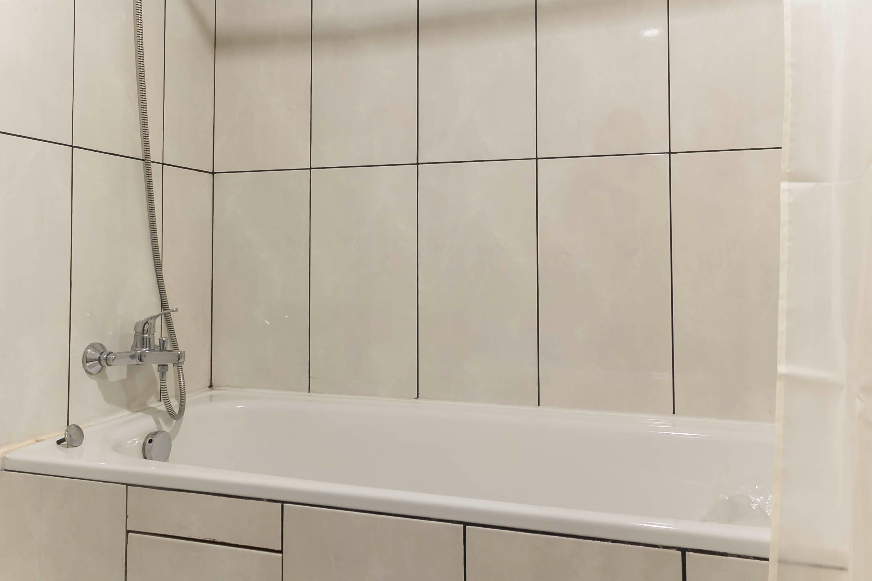 Ein Badezimmer mit Badewanne, gefliesten Wänden und einer Duschbrause.