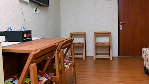 A room with a wooden table, two wooden chairs, a TV mounted on the wall, and a door. - Comfort Living And Strategic Studio At Kebagusan City Apartment (Jakarta)