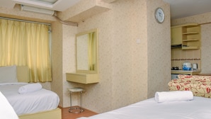 A hotel room with two beds, a small stool, a mirror, a clock, and a kitchenette area. - Comfort Living And Strategic Studio At Kebagusan City Apartment (Jakarta)