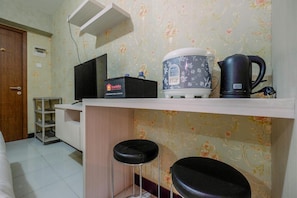A small kitchenette with a coffee maker, a travel-sized fridge, and a TV. - Relax And Homey Studio Room At Cinere Resort Apartment (Depok)