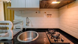 Una cocina con gabinetes blancos, un lavamanos de acero inoxidable, una estufa a gas y una campana extractora moderna.