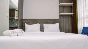 Una cama grande con sábanas y almohadas blancas, un cabecero de madera y una silla azul.
