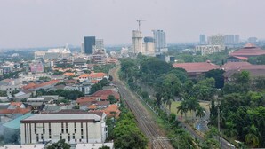 Un paisaje urbano con vías de tren, edificios y áreas verdes.