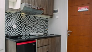 Una cocina compacta con encimera negra, lavavajillas integrado y salpicadero de azulejos.