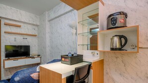 A compact hotel room with a television, a minibar, a microwave, and a coffee maker on the counter. - Homey And Simply 2Br Apartment At Cinere Resort (Depok)