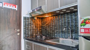 A kitchen with a stainless steel sink, a built-in stove, and a backsplash made of small, square tiles. - Homey And Simple Studio At Serpong Greenview Apartment (South Tangerang)