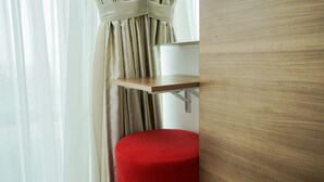 A wooden-framed mirror, a red ottoman, and a window with sheer curtains. - Nice And Elegant Studio At Tree Park City Apartment (South Tangerang)