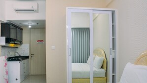A hotel room with a bed, a bathroom with a shower, and a kitchenette. - Comfy With Modern Style Springlake Summarecon Studio Apartment (Bekasi)