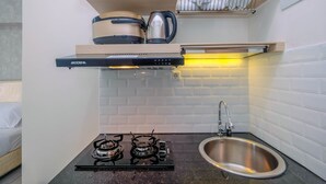 Une cuisine de taille réduite, équipée d’une cuisinière à gaz, d’un évier et d’une hotte aspirante.