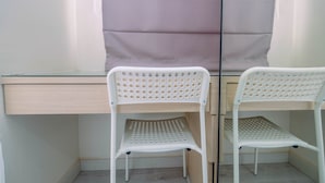 Un coin de pièce avec un mur miroitant, un bureau en bois et deux chaises blanches dont le dossier est ajouré.