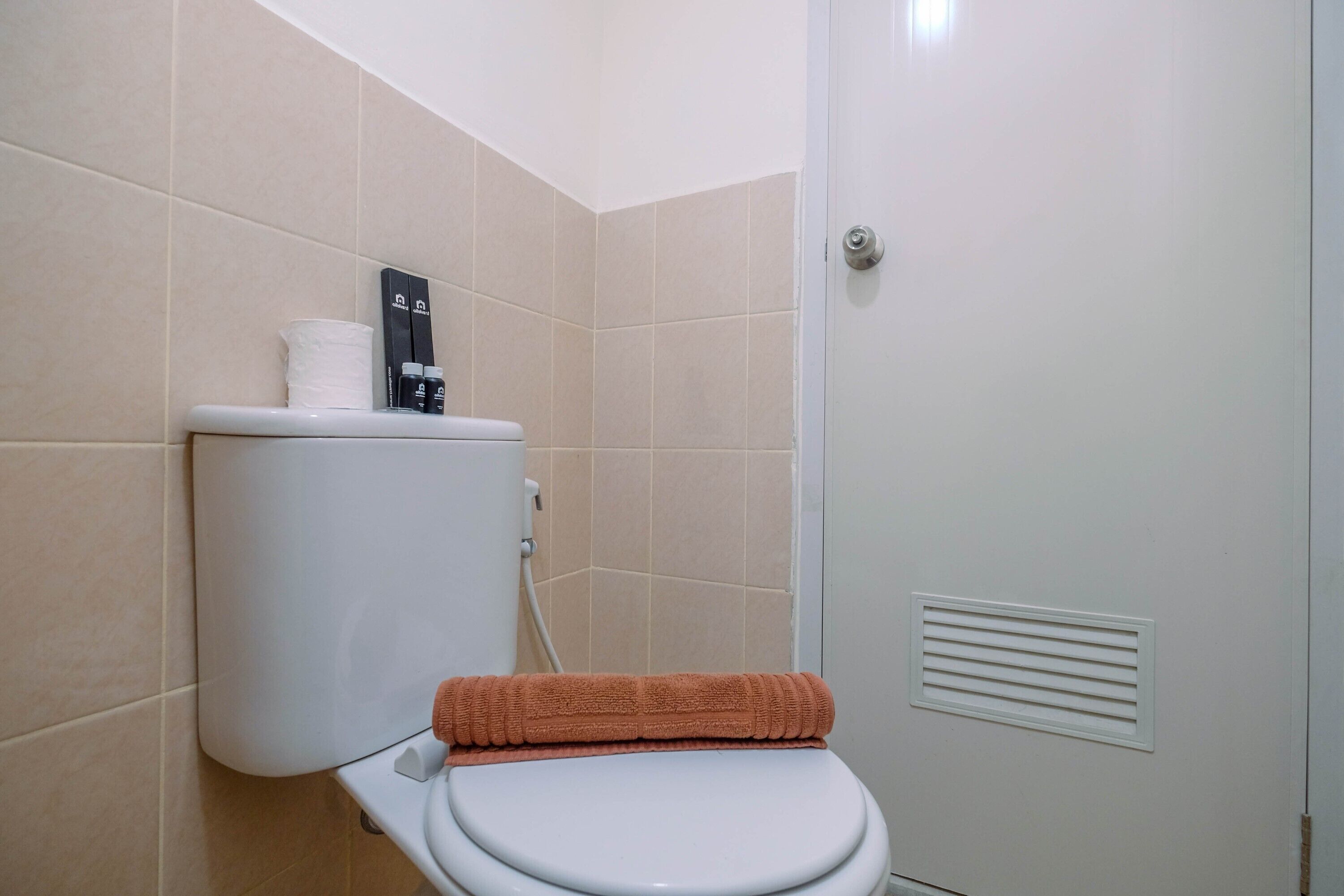 Un bagno con il water, un asciugamano e un porta carta igienica.