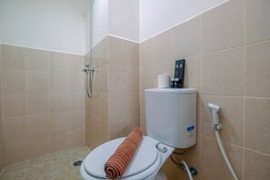 Bathroom features a toilet, shower area with handheld showerhead, and tile flooring.