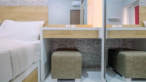 A modern hotel room with a bunk bed, a small stool, a mirror, and a brick wall. - Brand New Fabulous 2Br Podomoro Golf View Apartment By Travelio (Gunung Putri)