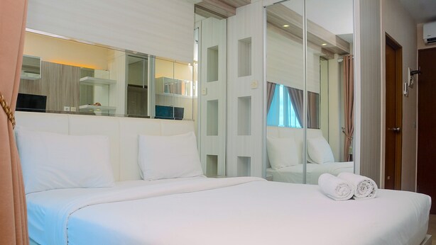 A hotel room with a large bed, a mirror, and a view of the outside. - Cozy With Good Location Studio At Tifolia Apartment By Travelio (Jakarta)