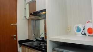 A compact kitchen with a stove, sink, and a kettle on the countertop. - Cozy With Good Location Studio At Tifolia Apartment By Travelio (Jakarta)